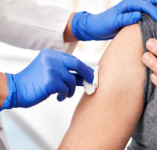 vaccine-picture A person receiving an injection from a syringe in a clinical setting.